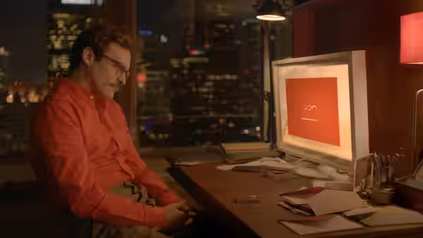 Theodore (Joaquin Phoenix) works at a desk with an old computer in a nighttime office