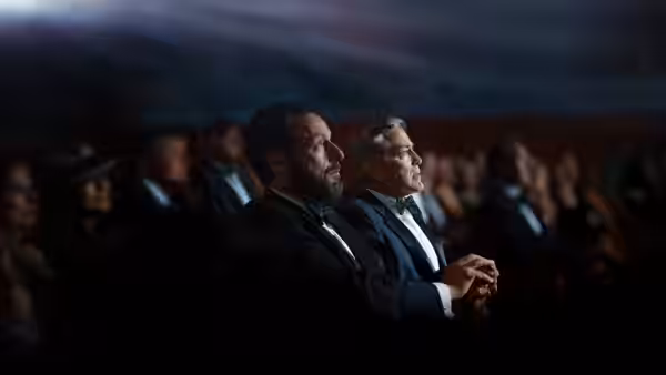 Ron Sukenick (Adam Sandler) and Jay Kelly (George Clooney) seated in a theater audience