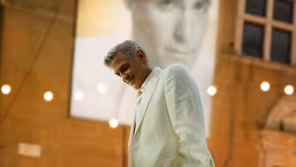 Jay Kelly (George Clooney) in a white suit looking down at an event