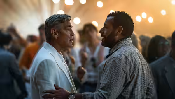 Jay Kelly (George Clooney) and Ron Sukenick (Adam Sandler) speaking closely at an event