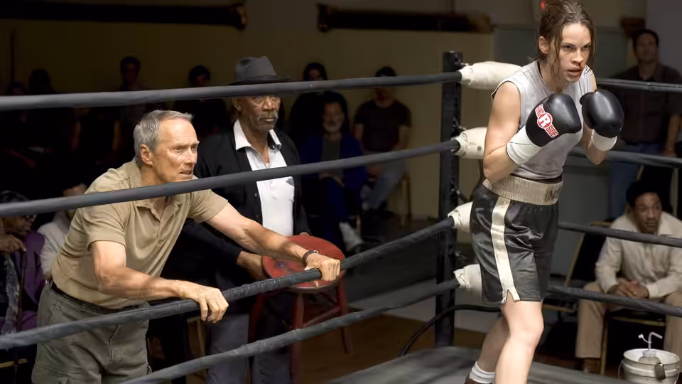 Frankie Dunn (Clint Eastwood) leaning on the ropes near Maggie Fitzgerald (Hilary Swank) in the ring