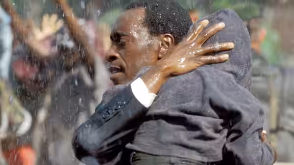 Paul Rusesabagina (Don Cheadle) hugging a person amid falling rain