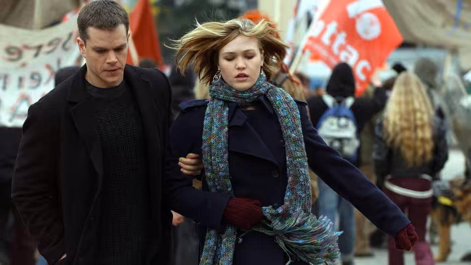 Jason Bourne (Matt Damon) guiding a woman through a crowded street protest