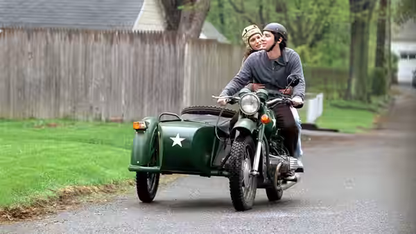 Andrew (Zach Braff) riding a motorcycle with sidecar carrying a passenger