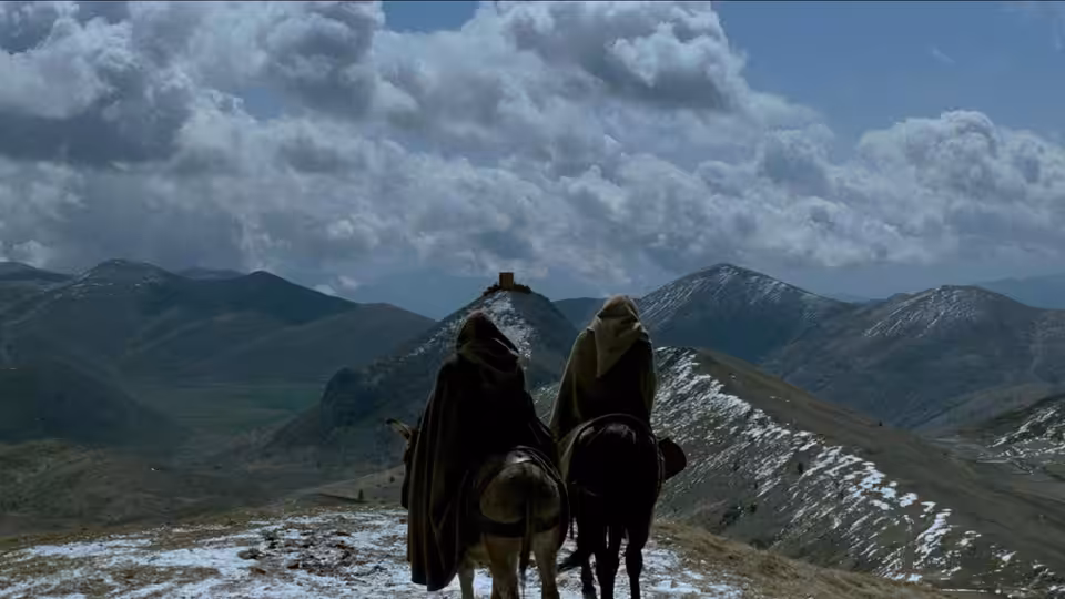 William of Baskerville (Sean Connery) and Adso of Melk ride toward a mountain monastery