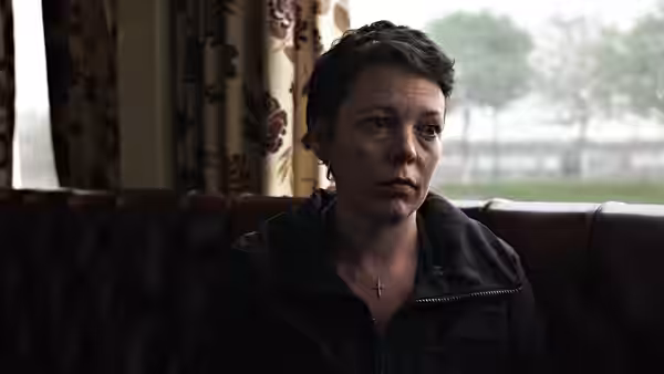 Hannah (Olivia Colman) seated on a leather couch looking ahead