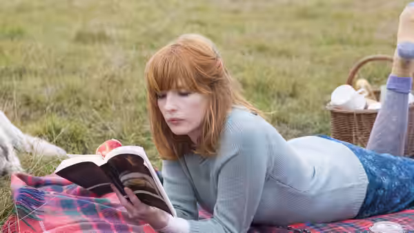 Fiona (Kelly Reilly) reading a book while lying on a picnic blanket