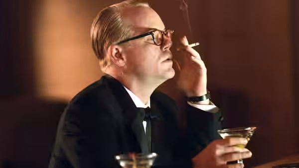 Truman Capote (Philip Seymour Hoffman) smoking a cigarette while holding a cocktail