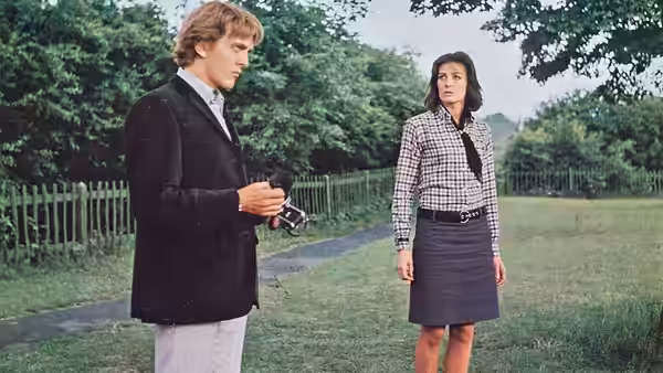 Thomas (David Hemmings) holds his camera beside Patricia (Sarah Miles) in a garden