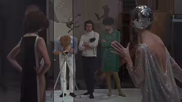 Thomas photographs a seated model while fashion figures watch in the studio