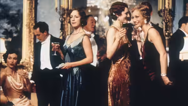 women in evening gowns hold drinks during a formal gathering