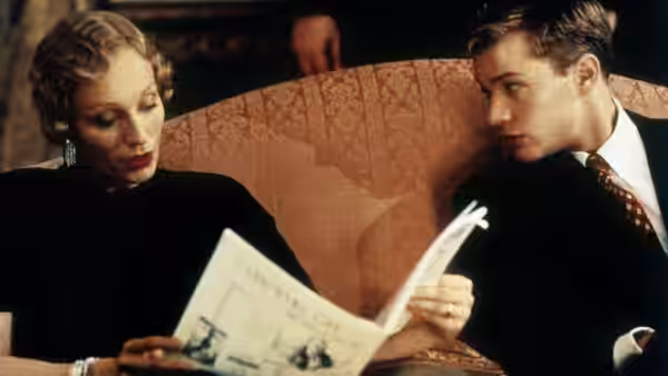 woman and man examine an open magazine while seated on a sofa