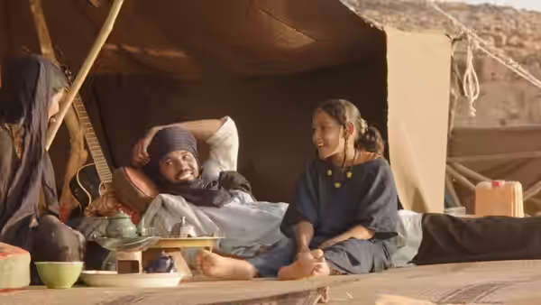 A man reclines inside a tent as a woman sits smiling beside him
