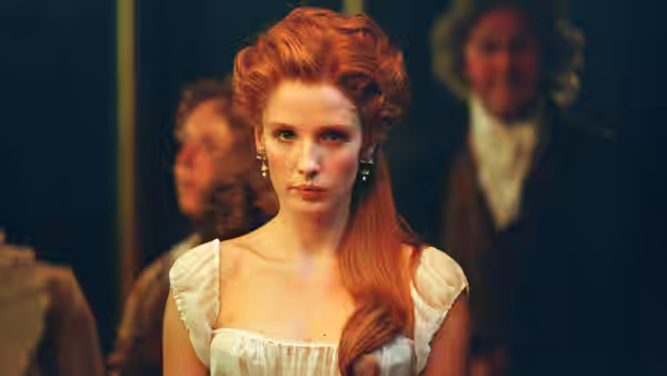 a red-haired woman in a white gown looking ahead at a gathering