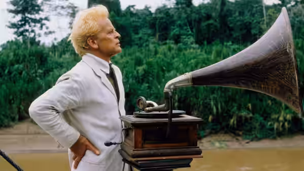 Fitzcarraldo (Klaus Kinski) listens to a gramophone beside a jungle river