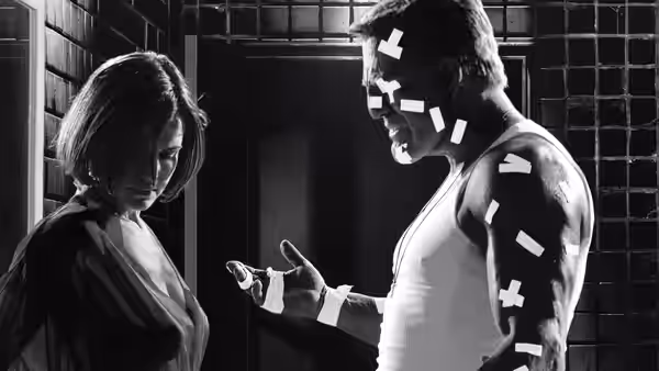 Hartigan (Bruce Willis) gesturing to a woman in a dark interior