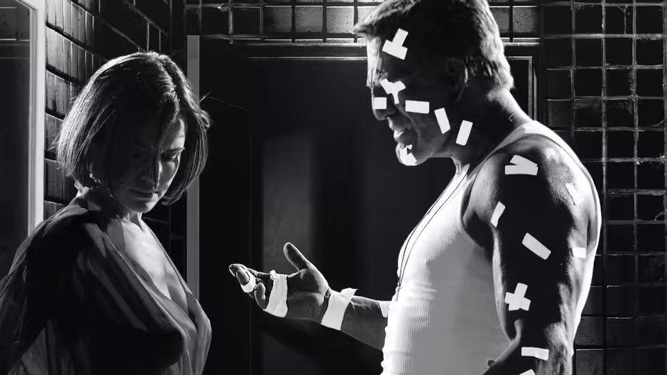 Hartigan (Bruce Willis) gesturing to a woman in a dark interior