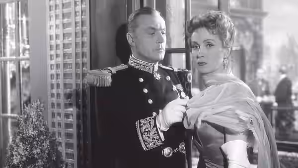 Général André de... (Charles Boyer) adjusts Comtesse Louise de... (Danielle Darrieux)'s shawl indoors