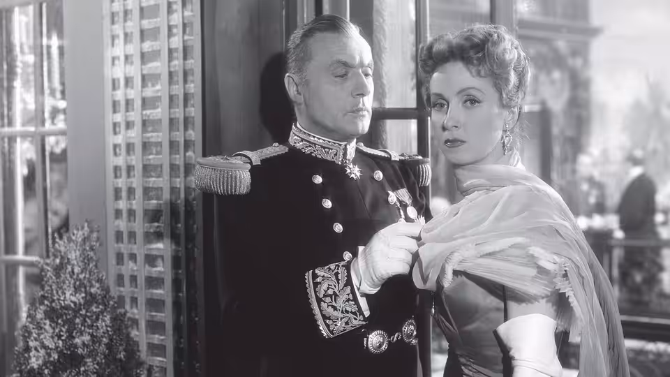 Général André de... (Charles Boyer) adjusts Comtesse Louise de... (Danielle Darrieux)'s shawl indoors