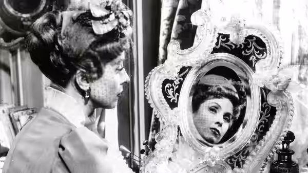 Comtesse Louise de... (Danielle Darrieux) looks into an elaborate dressing-table mirror
