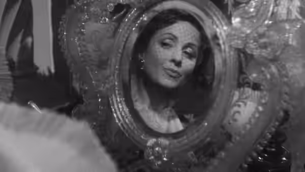 Comtesse Louise de... (Danielle Darrieux) admires herself in an ornate oval mirror