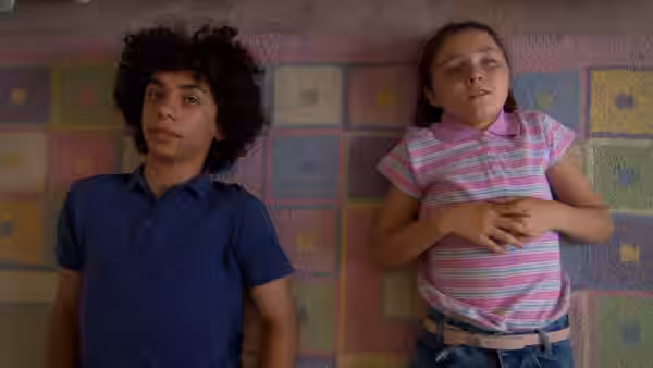 A boy and a girl leaning against a colorful checkered wall