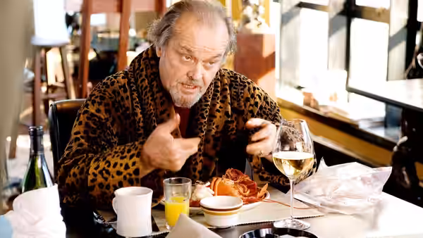 Costello (Jack Nicholson) gesturing while dining on lobster in a restaurant