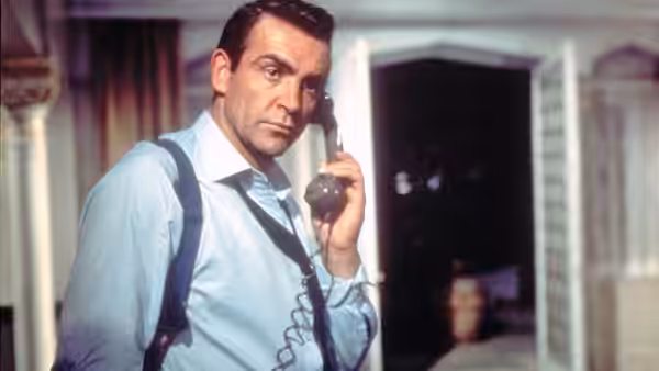 James Bond (Sean Connery) on the telephone in a light blue shirt and braces
