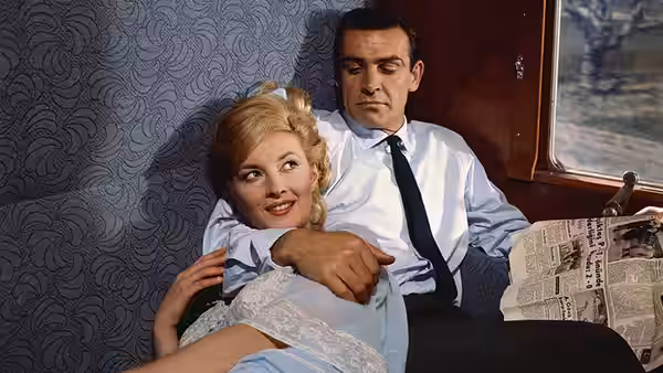 Tatiana Romanova (Daniela Bianchi) reclining with James Bond (Sean Connery) on a couch