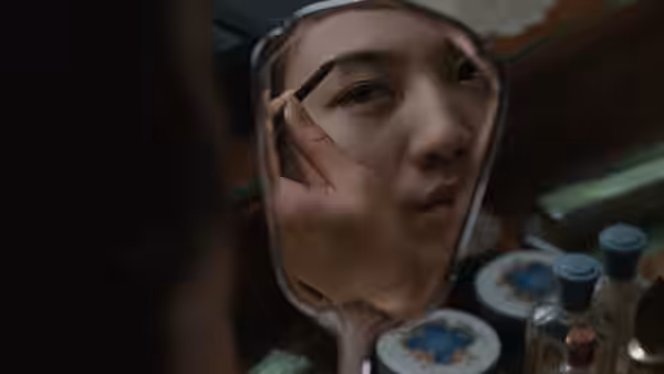 Wong Chia Chi (Tang Wei) studies her face in a hand mirror