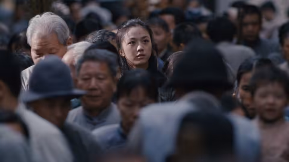 Wong Chia Chi (Tang Wei) looks ahead while surrounded by a crowded street