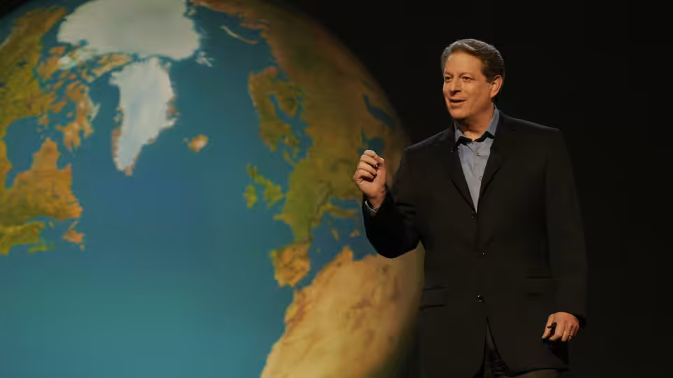 Al Gore gesturing while speaking in front of a large Earth projection