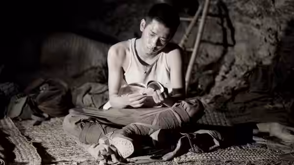 Private Saigo reading a letter while seated cross-legged in a cave