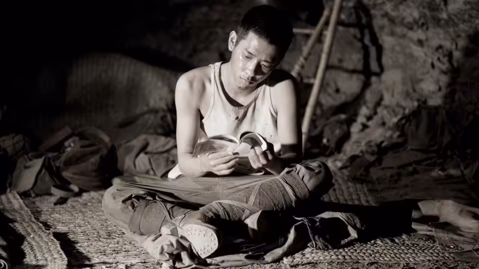 Private Saigo reading a letter while seated cross-legged in a cave