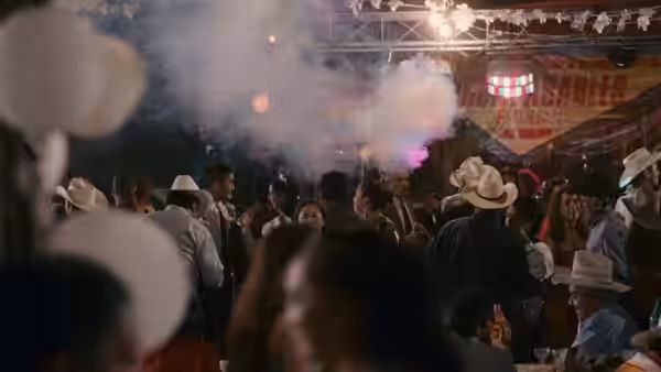 Crowd dances at a party with smoke and hanging banners