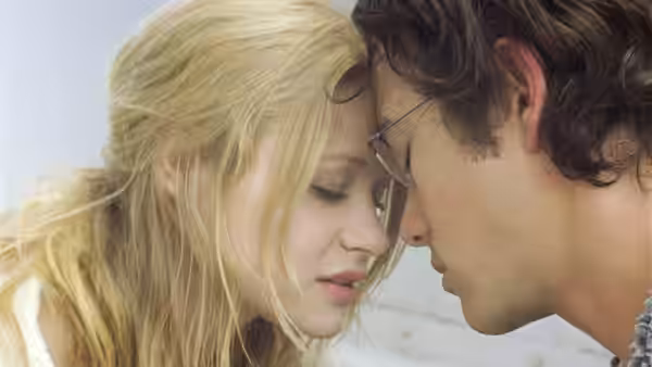 A young man with glasses pressing foreheads with a blonde woman
