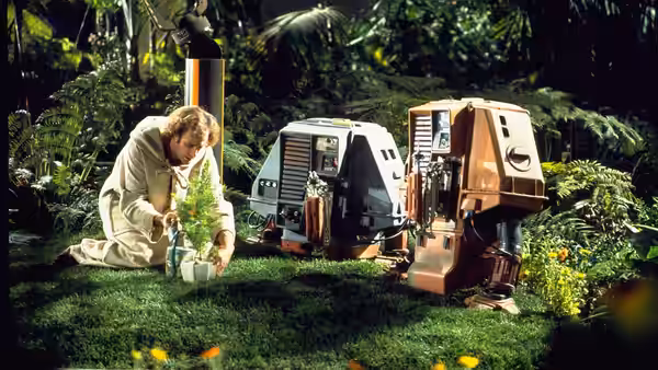 Freeman Lowell (Bruce Dern) kneeling to tend a plant with two drones