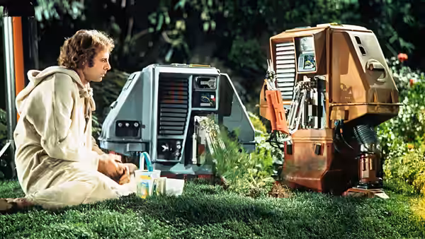 Freeman Lowell (Bruce Dern) sitting on grass with two drones among plants