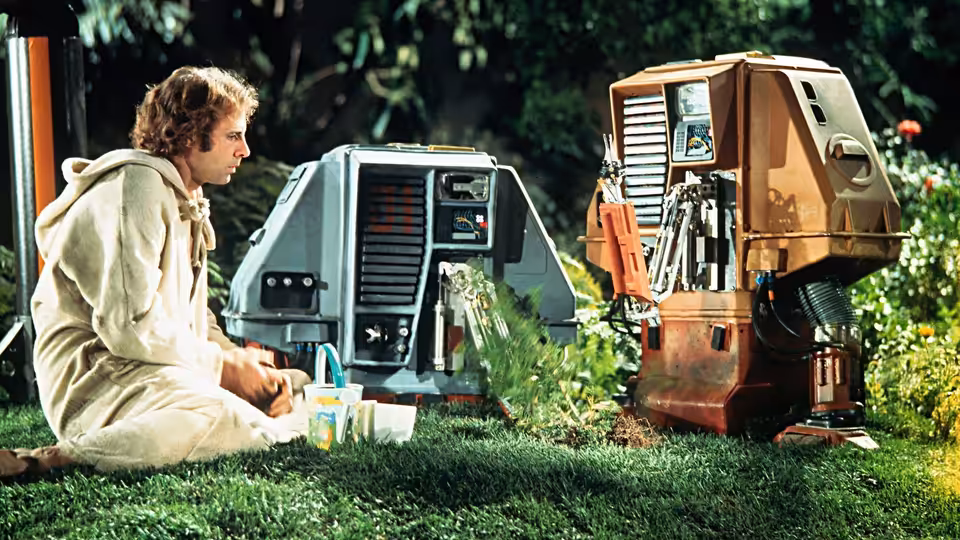 Freeman Lowell (Bruce Dern) sitting on grass with two drones among plants