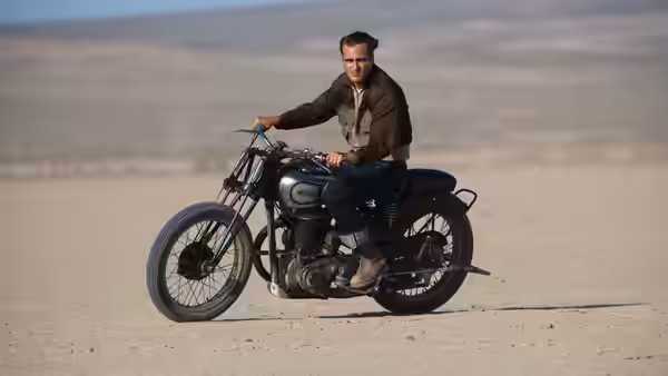 Freddie Quell (Joaquin Phoenix) rides a vintage motorcycle across a desert plain