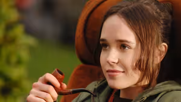 Juno (Elliot Page) holding a pipe and looking to the side outdoors