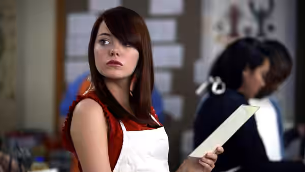 A young woman in a red top and apron holding a sheet of paper