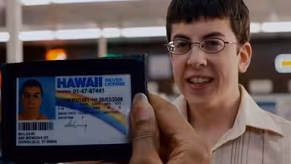 Fogell (Christopher Mintz-Plasse) holding up a fake Hawaii driver's license