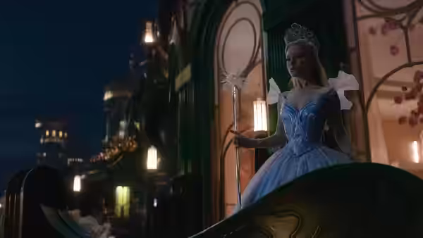 Glinda (Ariana Grande) holding a wand on a nighttime balcony