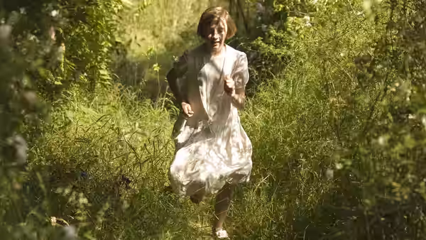 Briony Tallis (Romola Garai) running through sunlit woods in a white dress
