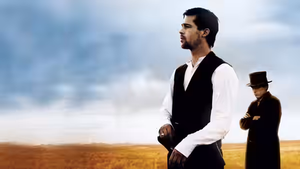 Jesse James (Brad Pitt) standing in open field with man in top hat behind