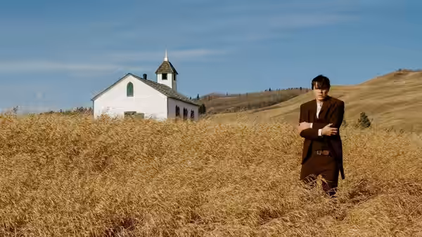 Robert Ford (Casey Affleck) standing in wheat field near white church