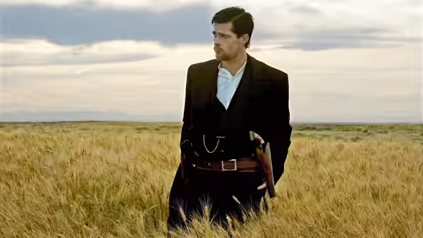 Jesse James (Brad Pitt) walking through tall wheat wearing dark suit