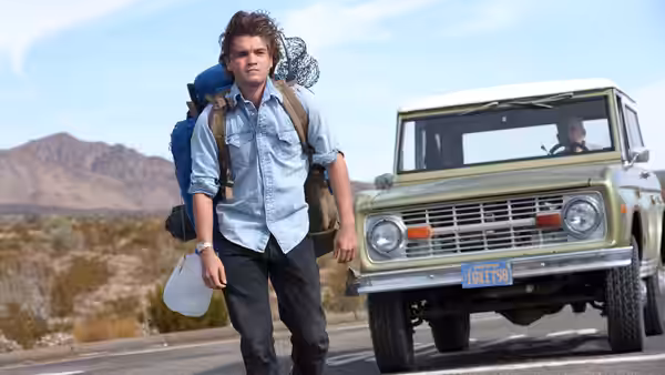 Christopher McCandless (Emile Hirsch) walking past a green truck on a highway