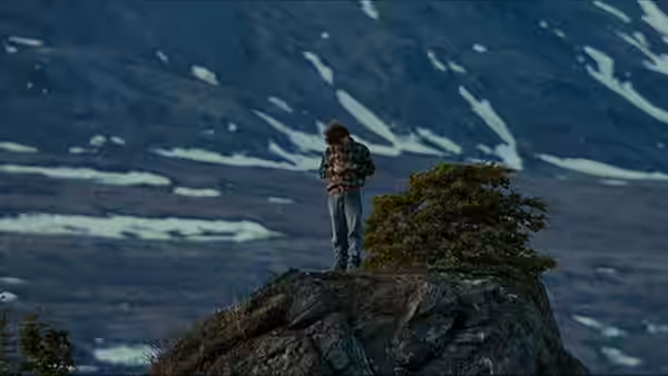 Christopher McCandless (Emile Hirsch) standing on a rocky ridge holding an object